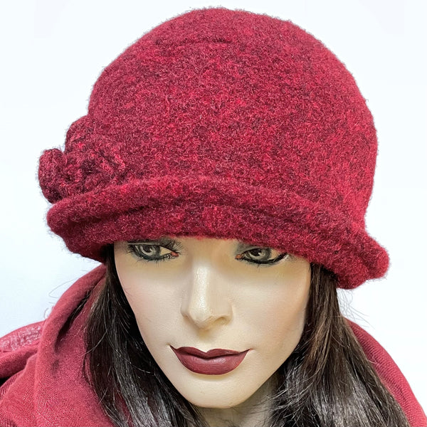 One-of-a-kind, handmade “Cloche” hat by Ottawa artisan Sue Scott. This modern 1920s style hat is fashioned in an acrylic and polyester blend fabric with a soft and cozy wool-like texture but without the itch and the colour is a rich heathered burgundy. It is finished off with a hand-sewn rosette and leaf trim in the same fabric and features a small, style-able brim. It is fully lined with wind-stopping kasha lining for added warmth. Size-small: Approximately 21 3/4.’’  Dry clean only.