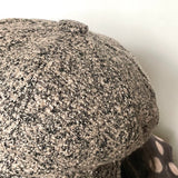 Button trim on top of the hat covered in same boucle fabric.