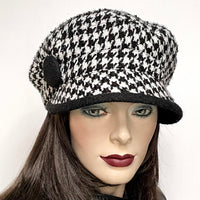 One-of-a-kind, handmade “Captain” hat by Ottawa artisan Sue Scott. It is fashioned in a woven houndstooth wool blend in black and white colours. The shape is a classic two-part crown with some volume and a nice smart peak. It is finished off with a large, black boiled wool-covered button on top that matches the underside of the peak and is lined with a thick, tightly woven wind-stopping kasha lining for added warmth. Size-small-medium: Approximately 22’’   