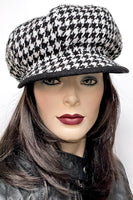 This one-of-a-kind hat, handmade by local artisan Sue Scott, is called the "Casquette". It is fashioned in a woven houndstooth wool blend in black and white. The shape is an eight-part voluminous crown, with a front peak. It is finished off with a large boiled wool-covered button on top in black that matches the underside of the peak. Fully lined with a Kasha lining that’s stops wind for added warmth. Size-medium: Approximately 22 ½’’ with an elastic in the back so it can go a little larger.  
