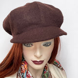 This one-of-a-kind hat, handmade by local artisan Sue Scott, is called the "Casquette". It is fashioned in a rich nut brown wool blend and the shape is a classic eight-part voluminous crown, with a front peak. The trim on top is a small vintage bakelite button in a matching brown colour. Fully lined with a satiny, flannel-backed Kasha lining that’s easy on the hair and stops wind for added warmth. Size-medium: Approximately 22 ½’’ with an elastic in the back so it can go a little larger.
