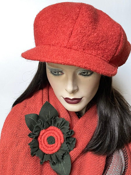 This one-of-a-kind hat, handmade by local artisan Sue Scott, is called the "Casquette". It is fashioned in a fun pumpkin orange boiled wool blend fabric with a cozy boucle texture. The shape is an eight-part crown, with some volume and a front peak. It is finished off with a covered button on top in the same fabric and is fully lined with a windproof Kasha lining. Size medium-large: Approximately 22 1/2’’ with an elastic in the back so it can go much larger. 