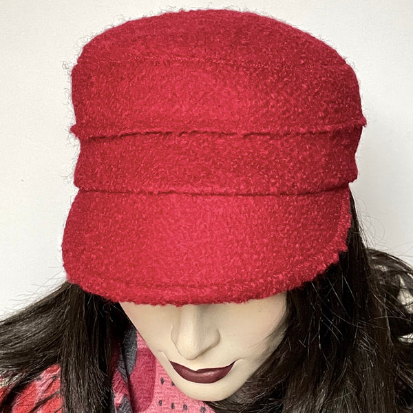 This one-of-a-kind hat, handmade by local artisan Sue Scott, is called the "Crumper". It is fashioned in a classic but fun red wool blend fabric with a cozy boucle texture which is perfect for adding a bit of colour. The shape is a straight-sided, flat-topped crown, with a classic front peak. It is finished with a satiny, flannel-backed Kasha lining that’s easy on the hair and stops the wind for added warmth. Size-medium: Approximately 22 1/2" Dry clean only.
