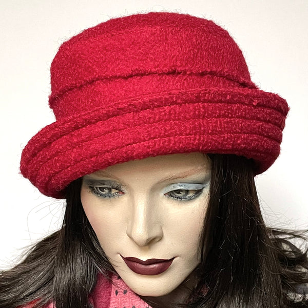 One-of-a-kind, handmade “Jojo” hat with a Stella brim by Ottawa artisan Sue Scott. It is fashioned in a classic but fun red wool blend fabric with a rich and cozy boucle texture which is perfect for adding a bit of colour to your outfits this winter. The shape is a straight-sided crown with a flat top and a Stella brim that is flexible and can be styled easily. It is fully lined with a thick flannel-backed wind-resistant Kasha lining that's also easy on the hair. Size-medium: 22 ½.’’