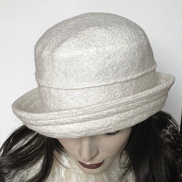 One-of-a-kind, handmade “Jojo” hat with a Stella brim by Ottawa artisan Sue Scott. It is fashioned in an easy-to-wear off-white wool blend with a beautifully soft and cozy texture. Elegance meets fun for easy day wear and evening and holiday looks too. The Stella brim is finished off with top stitching and can be styled easily. This hat is fully lined with a satiny, flannel-backed Kasha lining that’s easy on the hair and protects from the wind. Size-medium: 22 ½.’’