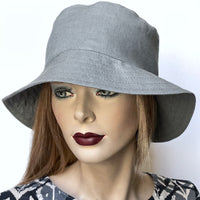 This one-of-a-kind bucket hat, handmade by local artisan Sue Scott, is called the "Nina". The fabric is 100% medium-weight linen in a beautiful and versatile medium grey shade. The shape is a classic bucket style with a straight-sided crown with a flat top and a medium brim that angles down for sun protection when styled flat or can be flipped and curved upwards. Super simple and easy to wear, the "Nina" is fully lined with satin. Size-medium: 22 1/2’’  