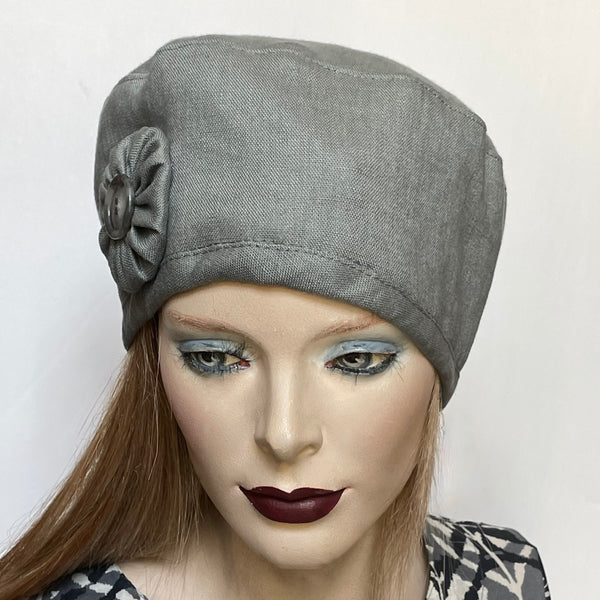 "One-of-a-kind, handmade “Rideau” beret by Ottawa artisan Sue Scott. It is fashioned in 100% mid-weight linen in a sophisticated and easy-to-wear medium grey shade perfect as the finishing touch to your summer outfit. It is finished off with a hand-sewn cockade rosette in the same fabric with a matching vintage button at its center. It has an adjustable interior ribbon and can be worn in various ways. Fully lined with satin. Size-medium: ranging from 21 ½’’- 22 ¾.’’