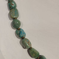 Closeup of strand of asymmetrical chunky turquoise and small round bronze beads