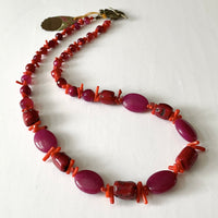 Find this one-of-a-kind, handmade necklace by local artisan Khalia Scott at Eclection Ottawa. This substantial necklace is carefully fashioned of tinted agate in a blend of red and magenta, tinted coral beads in the shape of tiny sticks and glass beads. It is beautifully finished with an intricate flower clasp made of oxidized bronze. It is strung securely by hand on a heavy coated multi-strand tiger tail cord. This necklace is matinee length measuring 26" around.