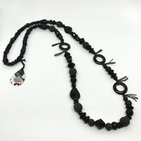 This one of a kind necklace is handmade by Ottawa artisan Khalia Scott. The colour theme is named "Mystery " and it is part of a collection inspired by Dr. Katie Bouman. It has natural lava beads, polished onyx "holes", faceted polished Czech glass beads, as well as ebony and ceramic beads all in black.  It is strung and knotted securely by hand on a dark mushroom coloured waxed cotton cord and is virtually metal free. It measures approximately 36.5" in length and slips easily over your head.