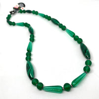 Find this one-of-a-kind necklace is handmade by Ottawa artisan Khalia Scott at Eclection Ottawa. It has natural, rare, polished and hardened semi-precious oblong malachite beads, vintage moulded glass and matte Tibetan glass beads all in a rich shade of green. It is finished off with small faceted zinc alloy beads and has a simple black metal two-part clasp. It is strung securely by hand on a heavy coated multi-strand tiger tail cord. It is matinee length measuring 25".