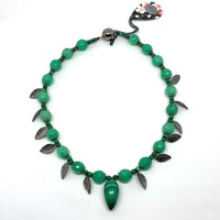 This one-of-a-kind necklace is handmade by Ottawa artisan Khalia Scott. It has natural, rare, polished and hardened semi-precious malachite beads and central pendant, faceted tinted agate beads, and small zinc alloy beads and findings.  It is strung securely by hand on a heavy coated multi strand tiger tail cord and has a spherical black metal two-part magnetic clasp. 16" long.