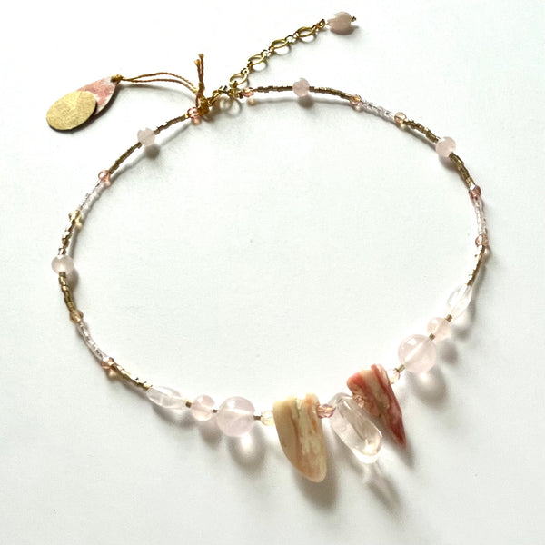Find this necklace handmade by local artisan Khalia Scott at Eclection Ottawa. This necklace has large natural and polished rose quartz and shell, mixed with different shapes of rose quartz, faceted Czech crystals and glass seed beads. It is strung securely by hand on a heavy coated multi-strand tiger tail cord and is finished off with a gold-plated lobster clasp, extender chain and findings. It measures approximately 15 3/4" in length with an extra 2" for the extender chain . 