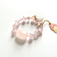 Find this handmade bracelet by local artisan Khalia Scott at Eclection Ottawa. It is carefully crafted out of rose quartz, faceted crystals and agates, presented with natural and polished chunky rose quartz at its centre and finished off with a gold plated leaf charm. It is carefully strung by hand on a heavy and durable elastic cord for comfy wear and ease of fit. Available in two sizes. The Small/Medium is approximately 6" in lenght