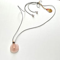 Find this handmade necklace by local artisan Khalia Scott at Eclection Ottawa. This necklace has a large natural and polished doughnut shape rose quartz and shell pendant, presented on a natural brown wax cotton cord finished off with polished rose quartz beads at each ends. It measures approximately 54" in length and can be tied at different lengths and can be worn in multiple ways. 