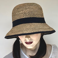 The “Critta” has a medium wireless brim that turns up at the edge but can also be worn down. It's made out of 100% natural crocheted seagrass in a naturally variegated shades of khaki and beige. Trimmed with a black grosgrain ribbon, interior band, adjustable elastic. - Size medium 22 1/2" - Brim 2 7/8" - Crown 4 1/2" high. At Eclection Ottawa