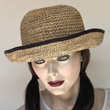 Find this flattering, versatile and packable hat at Eclection Ottawa. The “Critta” has a medium wireless brim that turns up at the edge but can also be worn down. It's made out of 100% natural crocheted seagrass. Trimmed with a black grosgrain ribbon, interior band, adjustable elastic. - Size medium 22 1/2" - Brim 2 7/8" - Crown 4 1/2" high