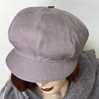 Find this handmade "Casquette" hat by local artisan Sue Scott at Eclection Ottawa.  It is fashioned in 100% lighter-weight linen in an easy-to-wear dusty lilac shade that brings colour to your spring and summer outfit. The shape is a classic eight-part voluminous crown, with a front peak that conveniently protects from the sun. The trim is a matching vintage button on top. Fully lined. Size medium/large at approximately 22 1/2’’ with elastic in the back so it can go larger.