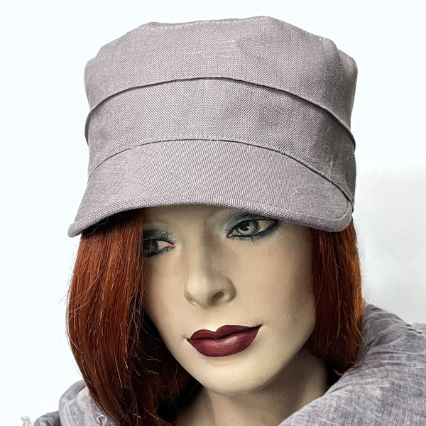 Find this Crumper cap handmade by artisan Sue Scott at Eclection Ottawa. It is fashioned in lighter weight 100% linen in an easy-to-wear dusty lilac shade that brings colour to your spring and summer outfits. The shape is a straight-sided, flat-topped crown, with a classic front peak that conveniently protects from the sun. This stylish cap is fully lined with satin and is a size medium at approximately 22 1/4’’