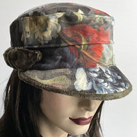 Find this one-of-a-kind Crumper hat, handmade by local artisan Sue Scott, at Eclection Ottawa. It is fashioned in a beautiful Baroque floral print in polyester panne velvet in tones of rust, greys, sage and plum. The shape is a straight-sided, flat-topped crown, with a classic front peak. It is trimmed with a hand-sewn knotted bow in the matching dark sage faux fur like the underpeak. It is fully lined with a satiny, flannel-backed, windproof Kasha lining. Size-medium 22 1/2" Dry 