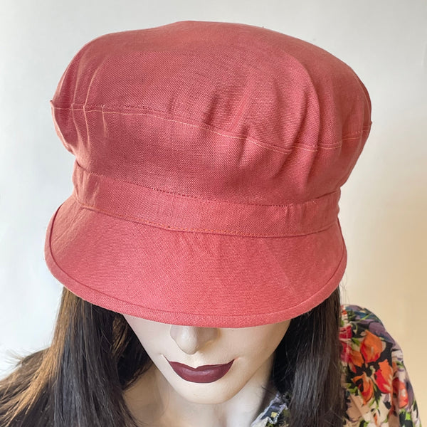 One-of-a-kind, handmade “Captain” hat by Ottawa artisan Sue Scott. The fabric is a mid-weight 100% linen in a beautiful shade of cameo pink.  Its shape is a classic two-part crown with some volume and a nice smart peak in front that protects from the sun. It's fully lined and is a size medium at approximately 22 1/2".  