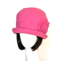 One-of-a-kind, handmade “Cloche” hat by Ottawa artisan Sue Scott. It is fashioned in a cheery candy pink wool/polyester blend which is a flattering pop of colour in the cold grey months. It is finished off with a handmade flower trim in the same fabric. This hat embodies the beautiful 1920’s classic style and adds a modern twist to it. It is lined with a satiny, flannel-backed Kasha lining that stops wind for added warmth and features a small brim. Size-medium: 22 ½.’’ Dry clean only.