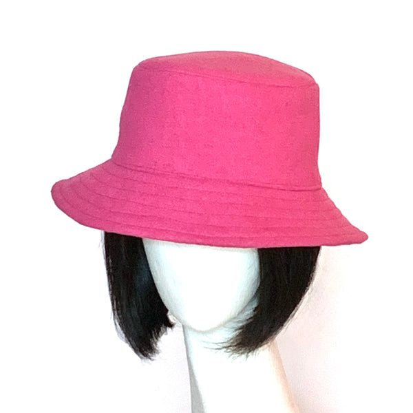 This one-of-a-kind hat, handmade by local artisan Sue Scott, is called the "Nina". The fabric is a wool/polyester blend in a candy pink shade and the shape is a classic bucket with a straight-sided crown with a flat top, with a medium brim that angles down to keep snow out of your eyelashes. Super simple and easy to wear, the "Nina" is fully lined with a satiny, flannel-backed Kasha lining that’s easy on the hair and stops wind for added warmth. Size-medium: Approximately 22 1/2". Dry clean.