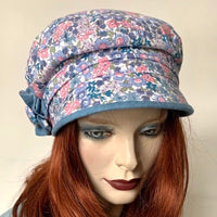 Fanfreluche Captain Hat in Pink and Blue Holly Hobby Cotton Floral, with Blue Rosette Trim.The shape is a classic two-part crown with some volume and a nice smart peak in front.  Original and handmade in Canada Hat.