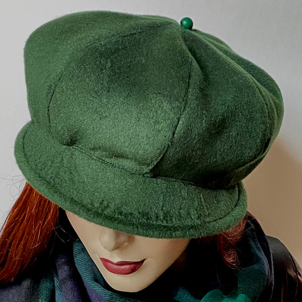 Find this one-of-a-kind Casquette, handmade by local artisan Sue Scott at Eclection Ottawa. It is fashioned in a rich and soft dark conifer green cashmere and wool blend fabric and the shape is an eight-part crown, with some volume and a front peak. It is finished off with a matching vintage button on top and is fully lined with a satiny, flannel-backed Kasha lining that’s easy on the hair and stops wind for added warmth. Size medium-large: Approximately 22 1/2’’ with an elastic in the back.
