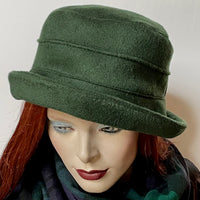 Find this one-of-a-kind, handmade “Jojo” hat with a Stella brim by Ottawa artisan Sue Scott at Eclection Ottawa. It is fashioned in a rich dark conifer green cashmere and wool blend fabric that will bring softness and colour to your outfit this winter. The shape is a straight-sided crown with a flat top and a Stella brim that is flexible and can be styled easily. It is fully lined with a thick and tightly woven windproof Kasha lining for added warmth. Size-medium: 22 ½.’’
