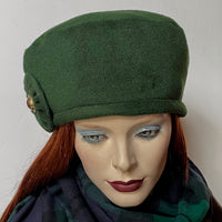 Find this one-of-a-kind, handmade “Rideau” beret by Ottawa artisan Sue Scott at Eclection Ottawa.  It is fashioned in a rich dark conifer green cashmere and wool blend fabric that will bring softness and colour to your outfit this winter. It is trimmed with a cockade in matching fabric with a gold-toned vintage button at its centre. It features an adjustable ribbon and is fully lined with a thick and tightly woven windproof Kasha lining for added warmth. Size-medium: ranging from 21 ½’’- 22 ¾.’’