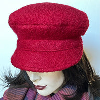 Find this One-of-a-kind, handmade “Captain” hat by local artisan Sue Scott at Eclection Ottawa. It is fashioned in a fun deep red wool blend fabric with a rich and cozy boucle texture which is perfect for adding a bit of colour in the wintertime. The shape is a classic two-part crown with some volume and a nice smart peak in the front. It is fully lined with a satiny, flannel-backed Kasha lining that’s easy on the hair and stops the wind. Size small/medium: Approx 22 1/4.’’   