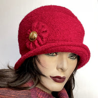 Find this One-of-a-kind, handmade “Cloche” hat by Ottawa artisan Sue Scott at Eclection Ottawa. This hat embodies the beautiful 1920’s classic style and is fashioned in a deep red wool blend fabric with a cozy boucle texture.  It is finished off with a handmade cockade trim with a vintage metal button at its centre and is fully lined with a satiny, flannel-backed Kasha lining that’s easy on the hair and stops wind and features a small, top-stitched style-able brim. Size-medium: Approx 22 ½.’’  