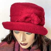 Find this one-of-a-kind, handmade “Jojo” hat with a Stella brim by Ottawa artisan Sue Scott at Eclection Ottawa. It is fashioned in a fun deep red wool blend fabric with a rich and cozy boucle texture and the shape is a straight-sided crown with a flat top and a medium size Stella brim that is flexible and can be styled easily. It is finished off with a hand-sewn knotted bow and is fully lined with a thick and tightly woven windproof Kasha lining that's easy on the hair. Size-medium: 22 ½.’’