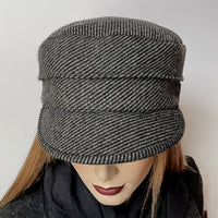 This one-of-a-kind hat, handmade by local artisan Sue Scott, is called the "Crumper". It is fashioned in a beautiful grey and black striped wool/cashmere blend fabric that add texture to this classic neutral hat. The shape is a straight-sided, flat-topped crown, with a classic front peak that conveniently keeps snow off of your eyelashes. It is fully lined with a satiny, flannel-backed Kasha lining that’s easy on the hair and stops wind for added warmth. Size-medium: Approximately 22 1/2" 