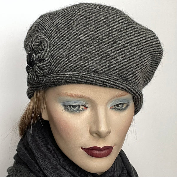 Find this one-of-a-kind, handmade “Rideau” beret by Ottawa artisan Sue Scott. It is fashioned in a grey and black striped wool and cashmere blend fabric. It is finished off with a hand-sewn cockade trim in the same fabric, adorned with a vintage button at its centre. It also features an adjustable ribbon so it can be worn in a variety of ways and accommodate different head sizes. It also sports a tightly woven windproof Kasha lining. Size-medium: ranging from 21 ½’’- 22 ¾.’’