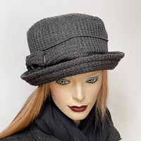 Find this one-of-a-kind, handmade “Jojo” hat with a Stella brim by Ottawa artisan Sue Scott at Eclection Ottawa. It is fashioned in a charcoal wool blend fabric with a waffle texture which adds a touch of coziness to this classic hat. The shape is a straight-sided crown with a flat top and a Stella brim that is flexible and can be styled easily. It is finished off with a hand-sewn gathered bow and is fully lined with a thick woven windproof Kasha lining. Size-medium: 22 ½.’’