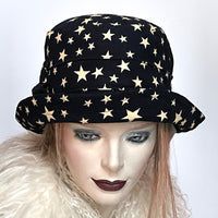 Find this one-of-a-kind, handmade “Jojo” hat with a Stella brim by Ottawa artisan Sue Scott at Eclection Ottawa. It is fashioned in a very fine cotton blend corduroy fabric with an allover star print in cream on an ink blue background. It features a flexible brim that can be styled easily. It is finished off with top stitching on the brim, an hand-sewn bow trim and is fully lined with a thick and tightly woven windproof Kasha lining. Size-medium: 22 ½.’