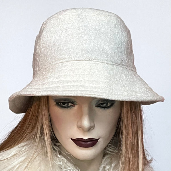 Find this handmade "Nina" bucket hat by local artisan Sue Scott at Eclection Ottawa.  It is fashioned in a classic winter white wool blend with a cozy texture in an off-white colour. The shape is a classic bucket with a straight-sided crown with a flat top and a medium brim that angles down  It is fully lined with a thick windproof lining that’s easy on the hair and stops wind for added warmth. Size-medium: Approximately 22 1/2". Dry clean only. 