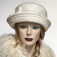 Find this one-of-a-kind, handmade “Jojo” hat with a Stella brim by Ottawa artisan Sue Scott at Eclection Ottawa. It is fashioned in a classic winter white wool blend with a beautifully soft and cozy texture. The Stella brim is flexible brim and can be styled easily. It is finished off with top stitching on the brim, a handsewn buckle bow trim and is fully lined with a thick and tightly woven windproof lining. Size-medium: 22 ½.’’
