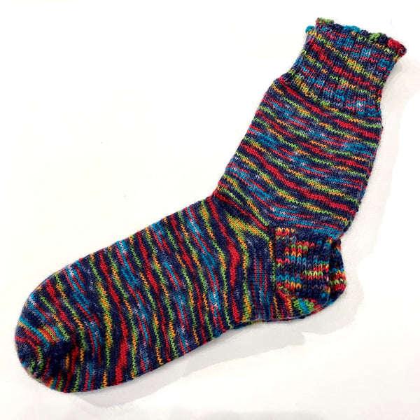Hand-knit one-of-a-kind socks by Stella Bedard, aka the British Hat Lady. Labours of love and knit with fine stitches in the best wool blends. No one makes them like this anymore. This pair of black, charcoal and rainbow multicoloured socks are knit with 70% wool and 30% nylon for durability. Length is 11 1/2’’, which is equivalent to a men’s size 11 shoe