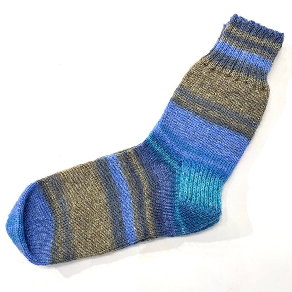 Hand-knit one-of-a-kind socks by Stella Bedard, aka the British Hat Lady. Labours of love and knit with fine stitches in the best wool blends. No one makes them like this anymore. This pair of variegated blues with taupe and charcoal socks are knit with 75% wool and 25% nylon for durability. Length is 10’’, which is equivalent to a men’s size 8 shoe and a women’s size 10.