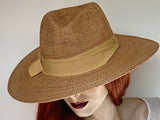 Find this charming Fedora hat at Eclection Ottawa. The “Jonni” is made out of braided paper with a naturally variegated look in a toast/tan colour, and trimmed with a large matching tan grosgrain ribbon. The shape is a classic fedora crown, and a large flat wired brim. With an adjustable elastic inside. Size of 22 1/4" to smaller. Brim 3 1/2. Crown 4 3/8".