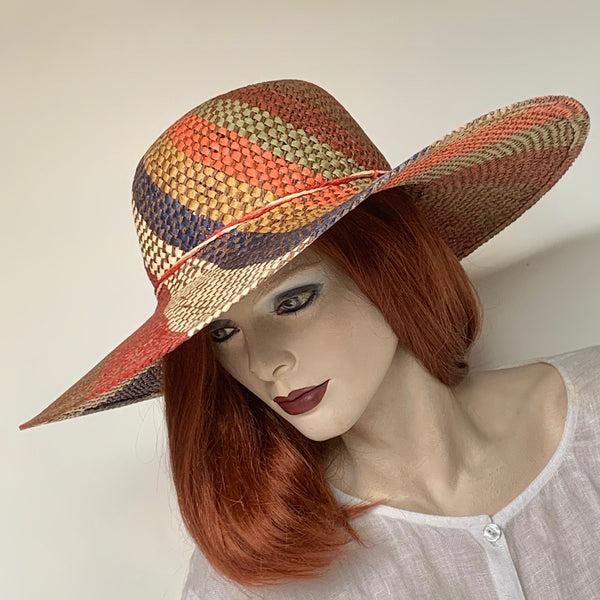 Find this statement hat at Eclection Ottawa. The “Copacabana”  is made out of woven paper in an open spiral motif in a mix of cocoa, ivory, navy, brick and orange. The shape is a flat domed crown with a large wired brim. Delicate twisted paper braids trim. Interior with adjustable elastic. Size 22 1/2" , Brim 5", Crown 4 1/4"