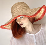 Find this flattering statement hat at Eclection Ottawa. The “Myrtle" is made out of 100% braided raffia pressed into a rounded dome crown. It has a large wireless brim with coral coloured fringe at the edge and a wide elastic interior band for some adjustability   Size 22 1/2" to smaller. Brim from 5" to 5 3/4". Crown 4 1/2".