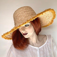 Find this flattering statement hat at Eclection Ottawa. The “Myrtle" is made out of 100% braided raffia pressed into a rounded dome crown. It has a large wireless brim with mustard yellow coloured fringe at the edge and a wide elastic interior band for some adjustability   Size 22 1/2" to smaller. Brim from 5" to 5 3/4". Crown 4 1/2".