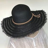 Find this versatile Black hat at Eclection Ottawa. The “Myrtle” is made out of paper braid in an open weave design with a matte texture. It has a rounded oval crown and a large wireless brim with fringed edge. Delicate braided round trims in a ultrasuede. With adjustable elastic. Size  22 3/8" to smaller. Brim 4 3/4". Crown 4 1/2".