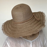 Find this versatile light brown/light cocoa hat at Eclection Ottawa. The “Myrtle” is made out of paper braid in an open weave design with a matte texture. It has a rounded oval crown and a large wireless brim with fringed edge. Delicate braided round trims in a ultrasuede. With adjustable elastic. Size  22 3/8" to smaller. Brim 4 3/4". Crown 4 1/2".