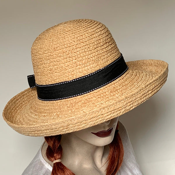 Find this flattering and charming hat at Eclection Ottawa. The “Zahra” is crafted out of sewn 100% finely braided natural raffia, and finished off with a black grosgrain trim with white top stitchings, hand tided in a bow with tails at the back. The shape is rounded cloche crown, and a downward kettle brim with a 1 1/2" edge that flips up. The bias interior band has an adjustable elastic inside that takes it from its maximum size of 22 1/2" to smaller. Brim 3 3/4" / Crown 4 1/2"