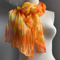 It has been created with Shibori dyeing technique on 100% pure silk crinkle chiffon and is totally unique. A piece of art to wear!  The silk chiffon is Summer weight (5 mm) and light and diaphanous with a crinkle texture that gives it body, interest, and charm. The finely finished hand-rolled piece measures flat at 22” X 72” but looks narrower with its crinkles. Mix of citrus orange, citrus yellow and a bit of white